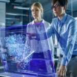 Male and Female Engineers Have Discussion while Using Modern Computer With Transparent Holographic Display. Monitor Shows User Neural Network Architecture Visualization. Shot in Modern Glass and Concrete Office.